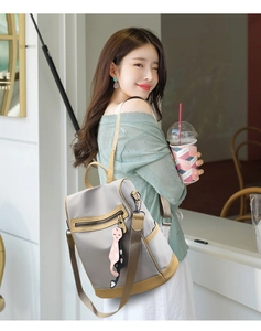Detail of grey nylon backpack with brown leather trim and cute cat charm in a cafe