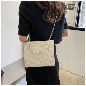 Close-up of cream chain tote bag with geometric 3D texture on model's shoulder