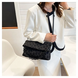 Détail de la texture jacquard floral noir sur un sac bandoulière avec chaîne épaisse