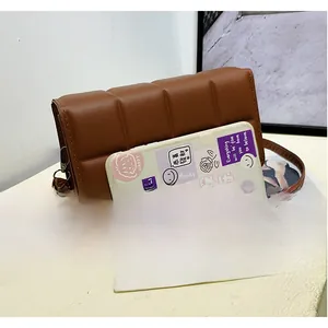 Brown quilted crossbody bag shown next to a smartphone for size comparison