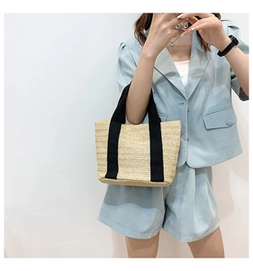 Detail of V-shaped straw weave texture and black canvas straps on a beige summer tote bag