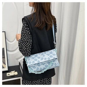 Détail du sac bandoulière bleu clair à fleurs avec une grosse chaîne en résine