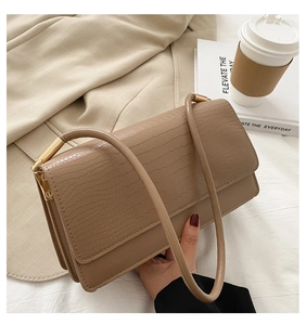Close-up of brown crocodile texture underarm bag with gold metal hardware details