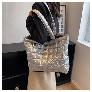 Silver quilted down tote bag worn by model showing large capacity and metallic texture
