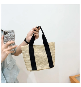 Detailed view of large straw tote bag with black canvas straps and chevron weave pattern