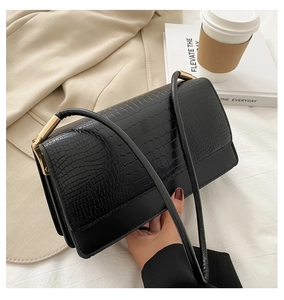 Close-up of black crocodile embossed bag with gold buckle on a stylish office desk