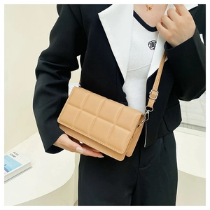 Side view of khaki quilted square crossbody bag with silver hardware on model
