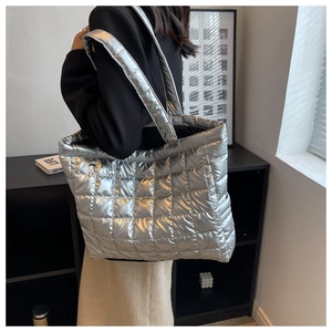 Silver quilted down tote bag worn by model, showing its large capacity and metallic texture