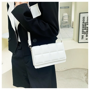 White quilted square bag with adjustable strap shown styled on a black blazer jacket