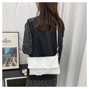 Détail du sac à rabat blanc avec texture florale 3D et chaîne épaisse en plastique