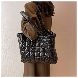 Close-up of black quilted puffer tote bag worn by a model in a minimalist style