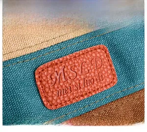 Gros plan détaillé du tissu en toile avec un patch logo en cuir orange sur le sac à main