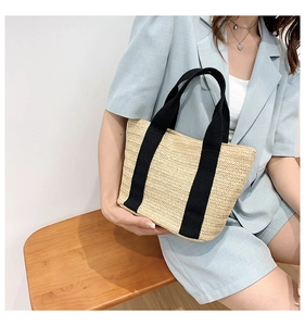 Straw tote bag with black strap handles styled with a blue suit for summer beach outings