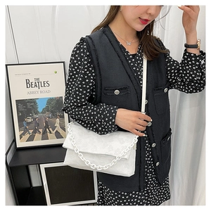 Détail du sac bandoulière blanc avec motifs floraux gaufrés et chaîne décorative chunky
