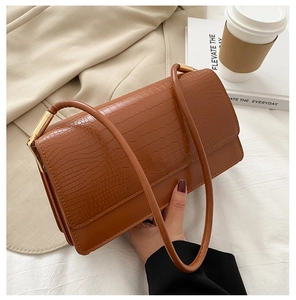 Detail of brown crocodile pattern embossed leather texture on a chic baguette bag