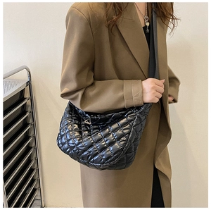 Detail of black quilted cloud shoulder bag showing glossy nylon fabric and triangle metal trim