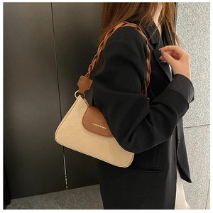 Detail of a chic two-tone underarm bag featuring a braided strap and gold hardware accents