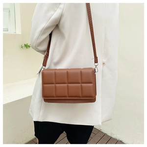 Close-up of brown quilted faux leather crossbody bag with adjustable shoulder strap