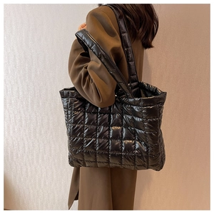 Detail view of a black quilted tote bag with soft padded texture and square stitching