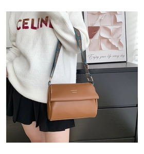 Détail du sac bandoulière en cuir marron avec large sangle fleurie de style vintage