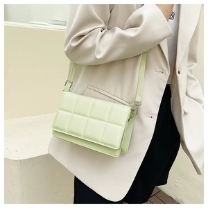 Detail of mint green quilted crossbody bag shown on a model with light suit
