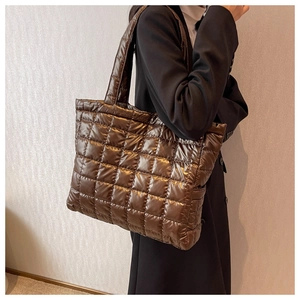 Detail of dark brown quilted down tote bag with puffer nylon texture and wide strap