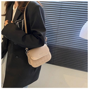 Detail of beige saddle bag with diamond quilting shown on a black oversize blazer