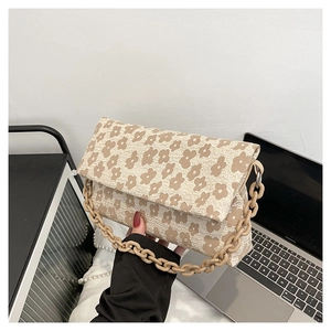 Détail du sac à main fleuri avec tissu texturé et bandoulière en chaîne épaisse