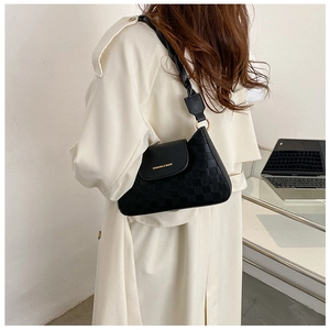 Detail of black waffle texture shoulder bag with woven strap shown on a model