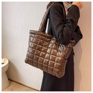 Detailed side view of a brown quilted glossy tote bag with stylish thick shoulder straps