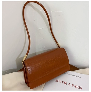 Detailed view of brown crocodile texture leather bag with elegant gold metal accents