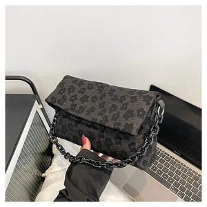 Détail du sac à main noir jacquard texturé avec grosse chaîne en résine et fleurs