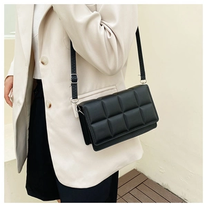 Detail of black quilted shoulder bag with adjustable silver buckle on slim strap