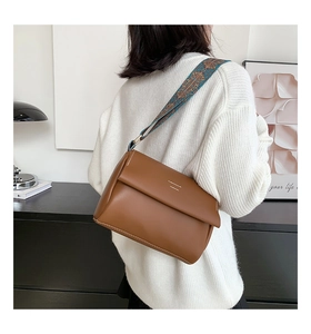 Détail d'un sac bandoulière en cuir marron avec bandoulière jacquard ethnique