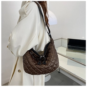 Detail of the glossy quilted texture and dual triangle zippers on a brown shoulder bag
