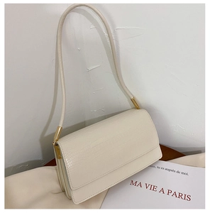 Detail of beige faux crocodile leather shoulder bag with gold hardware and flap closure