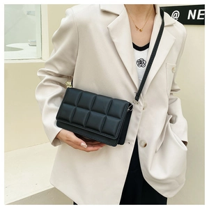 Detail of black quilted leather crossbody bag styled on a beige blazer outfit