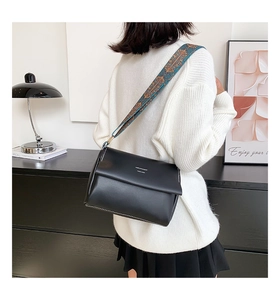 Détail du sac en cuir noir avec surpiqûres blanches et bandoulière jacquard ethnique