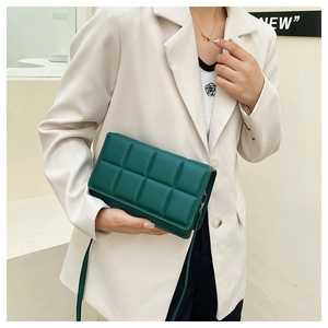 Model wearing dark green quilted leather crossbody bag with wide woven texture design