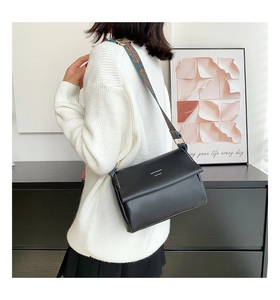Détail du sac bandoulière en cuir noir avec une large bandoulière tissée style ethnique