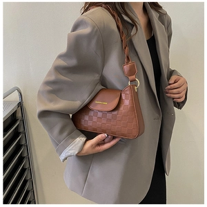 Detail of vintage brown leather underarm bag with checkered pattern and woven strap