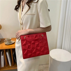 Red crossbody tote bag with geometric 3D pattern and gold chain strap in room setting