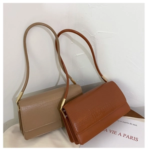 Detail of crocodile embossed faux leather baguette bags with elegant gold hardware rings