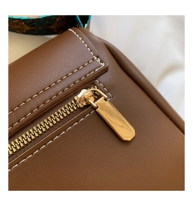 Détails d'un sac en cuir marron avec coutures blanches et bandoulière ethnique