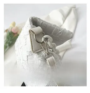 Close-up of high-quality silver metal hook and textured fabric detail on a white bag