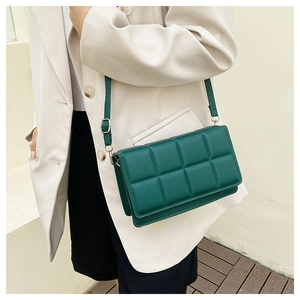 Detail of dark green quilted shoulder bag with soft padding and silver buckle on model