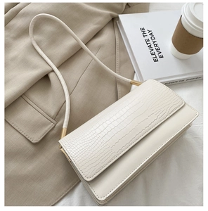 Close-up of white crocodile pattern shoulder bag with elegant gold metal hardware detail