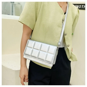 Close-up of a silver quilted crossbody bag with adjustable strap worn by a model