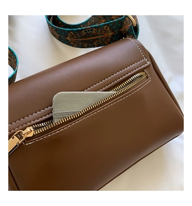 Détail du sac vintage en cuir marron avec poche zippée arrière et bandoulière tissée