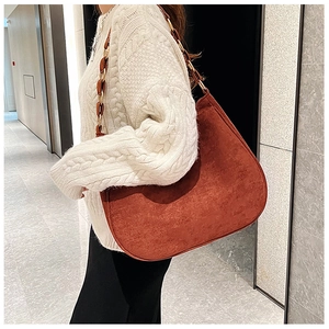 Detail of reddish-brown suede shoulder bag with gold chain and resin strap on sweater